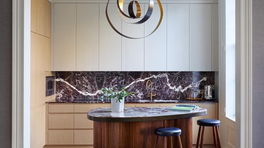 A kitchen wth a walnut slatted island unit, white painted wall units and oak veneer base and tall units 