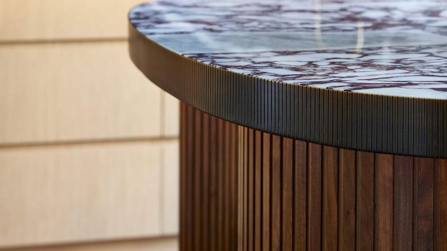 The edge of the marble worktop on the island is wrapped in a machined bronze band