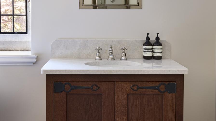 An Arts & Crafts inspired bathroom vanity units in dark stained oak with cream marble top 