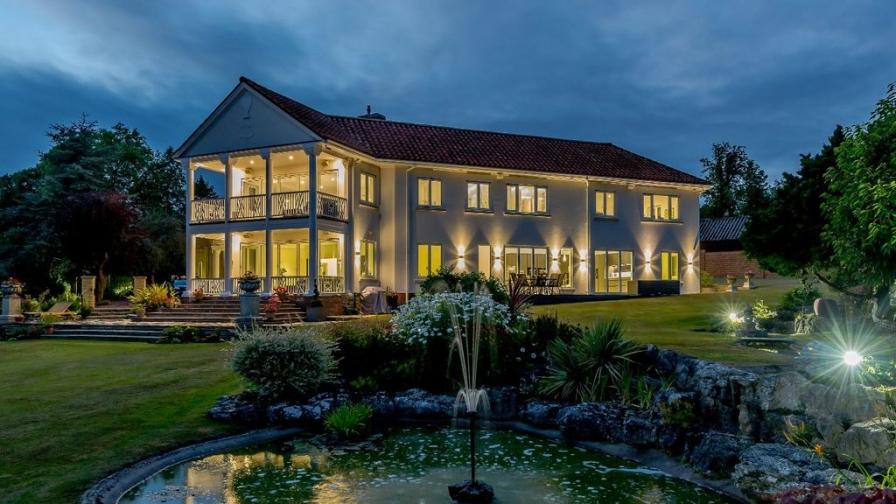 Shows inviting exterior of home at dusk, with lights on.